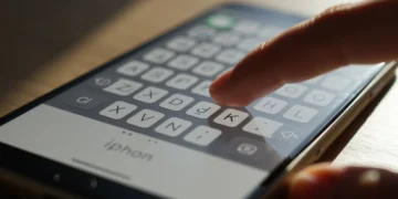 Mãos digitando rapidamente em um teclado virtual de iPhone, destacando a agilidade e eficiência.