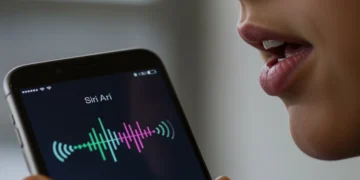 iPhone com a Siri ativa, mostrando o ícone de voz e a pessoa falando, sem tocar no aparelho, em um ambiente moderno.